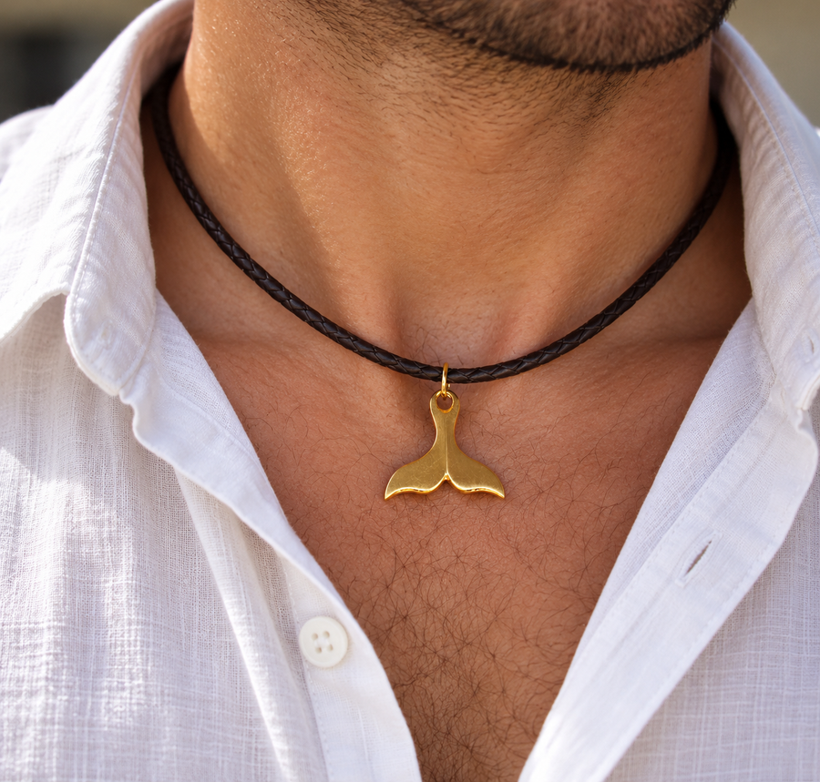 A double-strand braided dark brown leather bracelet with a polished gold-plated whale tail pendant, shown on a clean white background.