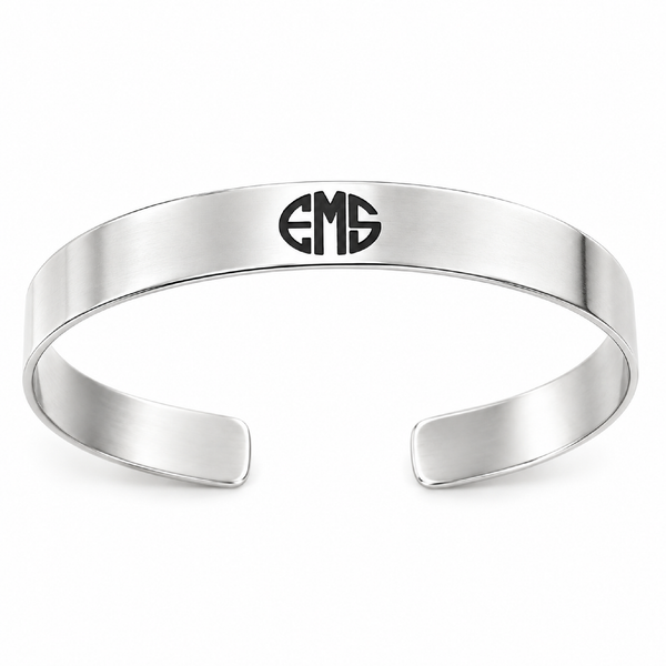 A polished silver-tone metal cuff bracelet with a black engraved monogram logo reading 'EMS' on the front, set against a clean white background.