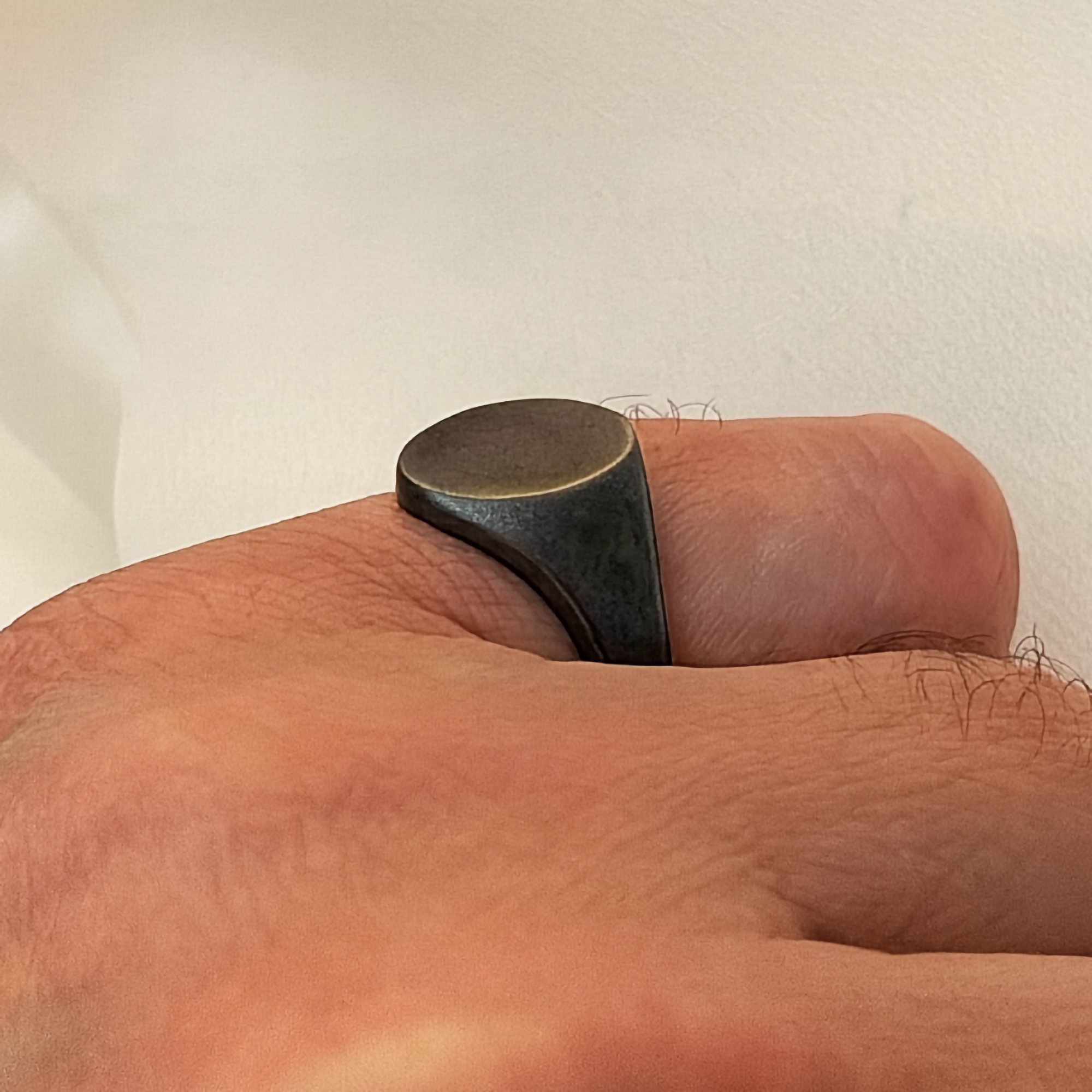 Close-up of a black ring on a person's finger against a neutral background