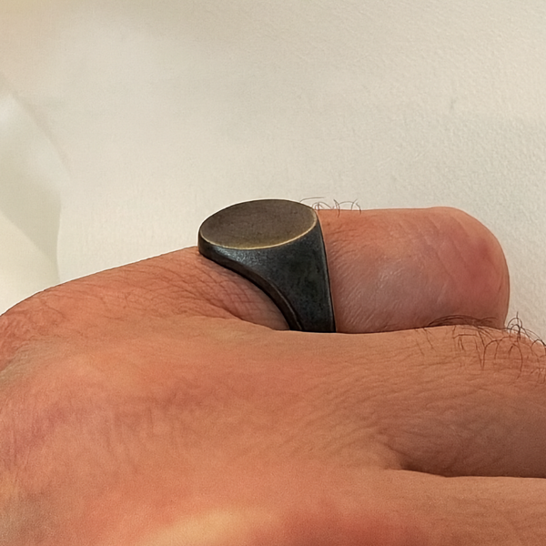 Close-up of a black ring on a person's finger against a neutral background